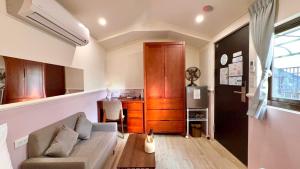 a living room with a couch and a kitchen at 櫻花樹夏民宿 in Zhunan