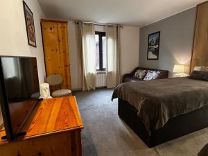 a bedroom with a bed and a tv and a couch at Devonshire Lodge Chalet in Bansko