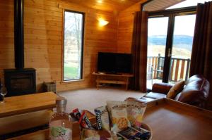 ein Wohnzimmer mit einer Couch und einem Tisch und einem Fernseher in der Unterkunft Woodland Oak Log Cabin, by Meall nan Tarmachan in Killin