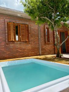 een blauw zwembad voor een bakstenen gebouw bij Casa quadra-mar com piscina in Rio Grande