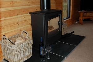 einem Holzofen mit zwei Weingläsern und einem Korb in der Unterkunft Woodland Oak Log Cabin, by Meall nan Tarmachan in Killin