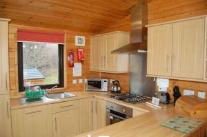 a kitchen with wooden cabinets and a sink and a stove at Woodland Oak Log Cabin, by Meall nan Tarmachan in Killin