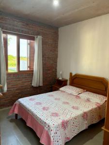 een slaapkamer met een bed en een bakstenen muur bij Casa quadra-mar com piscina in Rio Grande +6 foto's