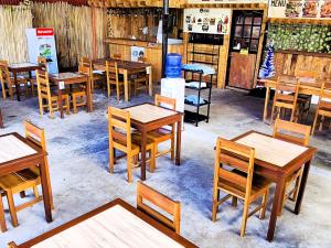 Green Turtle Backpackers Guesthouse, Puerto Princesa في مدينة بورتوبرنسس: مجموعة طاولات وكراسي خشبية في المطعم