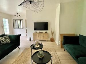 a living room with two green couches and a flat screen tv at L'Échappée Boisée - côté Vallée in Chambon-sur-Cisse