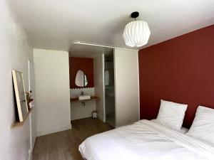 a bedroom with a white bed and a red wall at L'Échappée Boisée - côté Vallée in Chambon-sur-Cisse