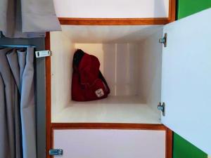Un sac à dos rouge se trouve dans un placard. dans l'établissement Green Turtle Backpackers Guesthouse, Puerto Princesa, à Puerto Princesa