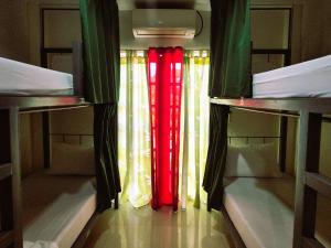 a room with two bunk beds with red and green curtains at Green Turtle Backpackers Guesthouse, Puerto Princesa in Puerto Princesa City