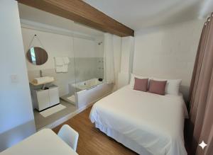 ein Schlafzimmer mit einem weißen Bett und einem Spiegel in der Unterkunft SUITES - Românticas na natureza para adultos in Itapecerica da Serra