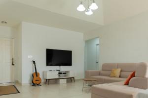 a living room with a couch and a tv and a guitar at Playa Dorada 3BR Home with Beach Club, pools, Garden with BBQ in ArraijÃ¡n