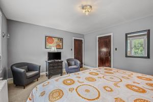 een slaapkamer met een bed en 2 stoelen en een televisie bij Aunt Bea's Bungalow - Pet Friendly - Hot Tub - Screen Porch - Wifi - Fenced Yard - King Bed - Town in Berkeley Springs