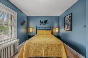 een blauwe slaapkamer met een bed en een raam bij Aunt Bea's Bungalow - Pet Friendly - Hot Tub - Screen Porch - Wifi - Fenced Yard - King Bed - Town in Berkeley Springs