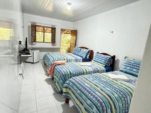 een kamer met drie bedden en een wastafel. bij Pousada Maré in Ponta do Mel