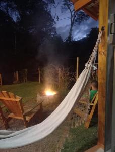 un uomo seduto su un'amaca in un cortile di Cabana Pouso Sereno a Domingos Martins