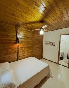 una camera con letto bianco e pareti in legno di Cabana Pouso Sereno a Domingos Martins