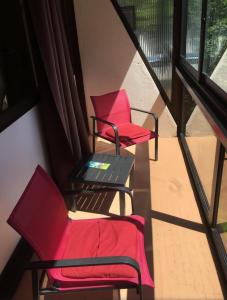 2 sedie rosse e un tavolo sul balcone di Le Chitelet vue sur pistes a Xonrupt-Longemer