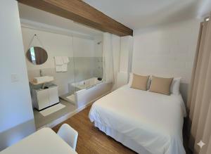 ein Schlafzimmer mit einem weißen Bett und einem Spiegel in der Unterkunft SUITES - Românticas na natureza para adultos in Itapecerica da Serra