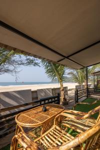 een tafel en stoelen op een balkon met uitzicht op het strand bij Deepiksha Beach Resort Talpona in Magdāl