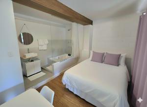 ein Schlafzimmer mit einem weißen Bett mit lila Kissen in der Unterkunft SUITES - Românticas na natureza para adultos in Itapecerica da Serra