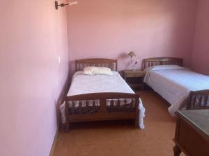 2 Betten in einem Zimmer mit rosa Wänden in der Unterkunft Habitaciones en Casa de la Playa! in Quintero
