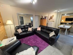 un soggiorno con mobili in pelle nera e un tappeto viola di Sandrina a Zagabria