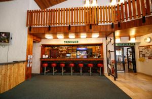 een restaurant met een bar met rode krukken bij Horský Hotel Neptun in Malá Morávka