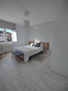 een witte slaapkamer met een bed en een stoel bij Tu Casina del Norte in Luanco