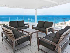een terras met stoelen en een tafel en de oceaan bij The Sebel Maroochydore in Maroochydore