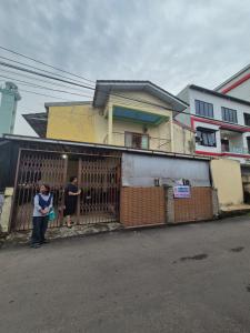 two people standing behind a gate in front of a house at Halim Living in Sukarami