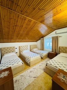 een kamer met 3 bedden en een houten plafond bij Villa Garden Shkodra in Shkodër