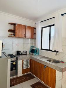 a kitchen with a sink and a stove and a window at Casses Apartments in Mombasa