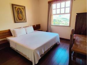 a bedroom with a large white bed with a window at Pousada Geraes in Ouro Preto