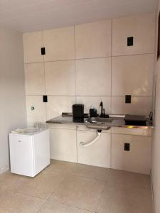 a kitchen with white cabinets and a sink at Pousada Serena Jacumã in Conde
