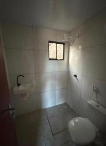 a bathroom with a white toilet and a window at Pousada Serena Jacumã in Conde
