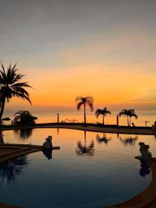een zwembad met palmbomen en een zonsondergang op de achtergrond bij Phangan Orchid Resort in Baan Tai +19 foto's