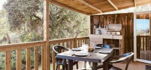 een tafel en stoelen op een terras met een keuken bij La Vetta Village Vacances Camping in Porto-Vecchio