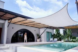 een vrouw die voor een huis met een zwembad staat bij Gaia Casa de Mar in El Bobo