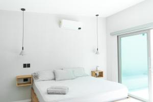 een witte slaapkamer met een bed en een raam bij Gaia Casa de Mar in El Bobo +62 foto's