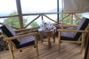 einen Tisch und zwei Stühle auf einer Veranda mit Aussicht in der Unterkunft My Hill Eco Lodge in Ruhengeri