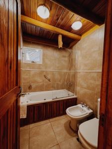 een badkamer met een bad, een toilet en een wastafel bij Cabañas Aike in Caviahue