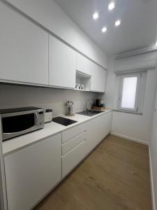 a kitchen with white cabinets and a microwave at Dorado Home in Scafati +1 photo