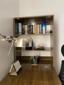 a desk with a lamp and a book shelf with books at The Flamingo 2 in Jos