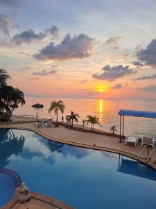 een zwembad met een zonsondergang boven de oceaan bij Phangan Orchid Resort in Baan Tai