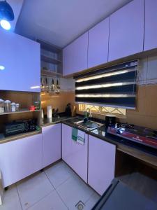 a kitchen with white cabinets and a sink at The Flamingo 2 in Jos