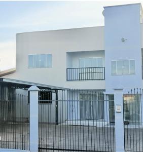 ein weißes Gebäude mit einem Zaun davor in der Unterkunft Ap Conforto no Centro de Sinop in Sinop + 5 Fotos