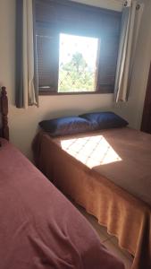 une chambre avec deux lits et une fenêtre dans l'établissement Casa IRIRI, à Anchieta