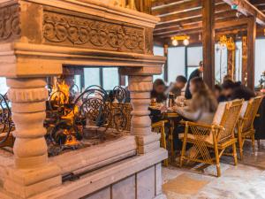 NarCappanar Cave Hotel的餐厅里的一个壁炉,人们坐在桌子上 更多23张照片