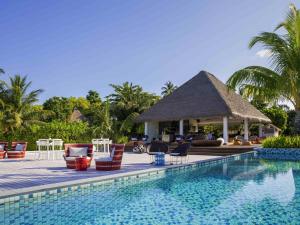 een zwembad in een resort met stoelen en een prieel bij Mercure Maldives Kooddoo - Adults-Only Escape - 50 percent off Domestic Transfers in Gaafu Alifu Atol