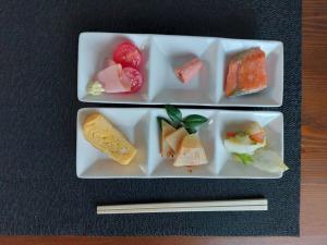Twee borden met eten op tafel, met eetstokjes. bij ゲストハウス凪季のやど in Nachikatsuura