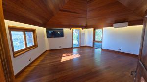 een lege woonkamer met houten vloeren en ramen bij Villa Serenitas in Arona